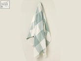 A soft pastel block check merino lambswool throw in light blue and white with fringed edges perfect for cozying up