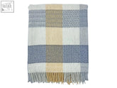 A soft patchwork merino lambswool throw in blue beige and gray plaid with herringbone and dot textures