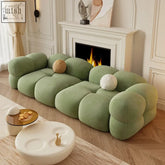 A plush sage green paten sofa with rounded cloud like cushions and soft velvet texture with ergonomic structure
