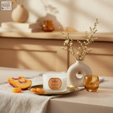 A white peach and amyris travel candle with coreless clean-burn technology on a gold tray with a gold label