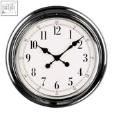 A sleek round wall clock with a chrome finish wall frame and white face featuring black numerals and hands by pelo