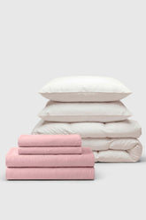 A soft pink and white percale move-in bedding set with neatly folded sheets duvet cover and matching pillows