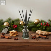 Clear glass reed diffuser with black reeds and dark green winter cinnamon label by relax perfect presents warm gingerbread scent