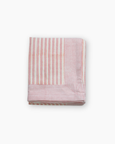 A neatly folded pink stripes roza print cotton tablecloth with embroidered wheat motifs along the border