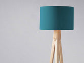 Teal cylindrical plain teal lampshade mounted on a light wooden tripod base perfect for table lamp use