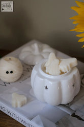 White ceramic pumpkin wax melt burner with black star decals holding ghost and bat wax melts for pumpkin spice fragrance oil