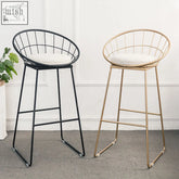 Two rafael sphere bar stools with wireframe metal frames in black and gold and cushioned white seats