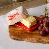 Cream-colored mini ceramic butter dish with red speckles and lobster design on matching red base holding butter