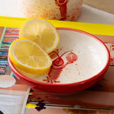 Red lobster mini ceramic dish with a white interior lobster design holding two lemon halves in a red bowl