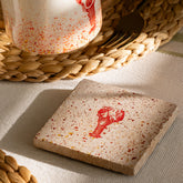 A square heat resistant natural limestone coaster with a red lobster imprint perfect for drink protection