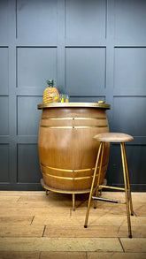 A rustic wooden half barrel bar with gold metal bands and a pineapple centerpiece for a retro home man cave
