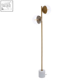 A sleek revive two light floor lamp with a gold finish brass pole and two clear glass globe shades at different heights
