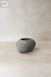 A smooth rounded gray stone planter pot with rough texture and dark interior perfect for direct planting