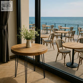 Round solid wood table with black hairpin legs and white vase with greenery perfect for bulk order cafes and restaurants