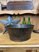 A rustic dark gray metal planter with a worn patina sits on a wooden shelf perfect for herbs or kindling storage