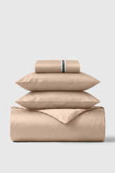 Beige satin sheet set with subtle striped accent band on pillowcase in the sateen essentials bedding set