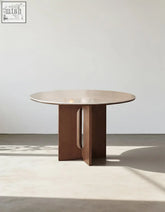 Sato round dining table with a light travertine stone top and dark brown wooden base featuring vertical cutouts