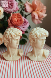 Two cream-colored scented david bust candles with detailed sculpted hair and wicks as unique bust candles