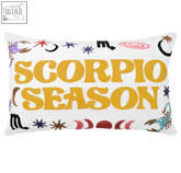 White rectangular pillow with bold yellow scorpio season text and colorful zodiac symbols in a scorpio season needlepoint cushion