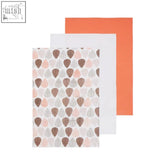 Set of three orange leaf tea towels with fabric napkins in soft pink patterned, solid white, and solid orange colors