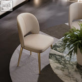 Cream-colored shankar leather dining chair with slender gold-tone metal legs perfect for stylish dining spaces