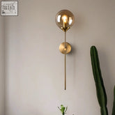 Brass-finished sizzle glass wall light with spherical amber glass globe and exposed filament bulb for warm ambient lighting