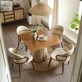 Warm-toned skylar rattan dining table with woven rattan base and four cream upholstered chairs with cane backrests