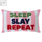A rectangular sleep slay repeat needlepoint cushion with pink and white stripes and colorful embroidered text