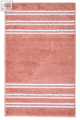 Coral-colored bath mat with white stripes in dusky pink perfect as a soft pink bath mat for your bathroom