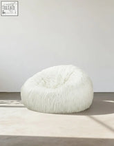 Soft bean bag armchair and stool with plush white faux fur and fluffy rounded shape for cozy lounging