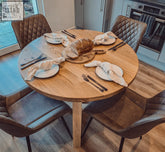 Solid oak round dining table with wooden legs surrounded by four brown quilted leather chairs