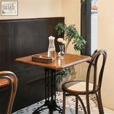 A solid wood sonnet dining chair next to a square wooden table with dark brown finish and black metal legs