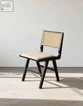 Black-framed sophia rattan dining chair with woven cane back and beige upholstered seat for dining room use