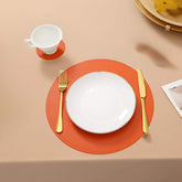 Orange leather placemat from sophistimat orange with subtle stitched edge under white plate and gold utensils