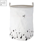 White canvas fabric laundry basket with black splash points and out embroidered in cursive speckled fabric laundry design