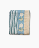 Folded splash blue block printed rozablue tablecloth with teal and cream stripes and white dandelion motifs on soft blue