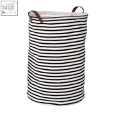 Black and white striped laundry bag with brown leather handles in cylindrical shape perfect for organizing clothes