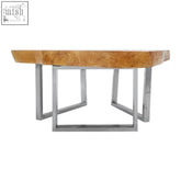 A sleek Surak teak wood coffee table with warm golden-brown wood top and minimalist stainless steel legs