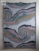 Swirls blanket soft woven throw with abstract pink teal and gold patterns on gray background with fringed edges