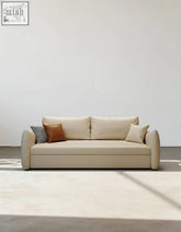 Beige leather tanak two seater sofa bed with rounded arms brown pillow and black and white checkered throw