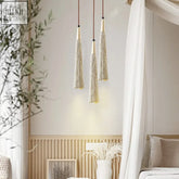 Three elegant gold-toned tassel pendant lights with metallic threads perfect for dining areas tassi light