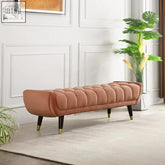 A sleek tb15 orange bench with rose gold velvet tufted upholstery and dark wooden legs with brass accents
