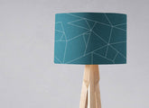 Teal table lamp with white line geometric design and light wood tripod lamp base perfect for ceiling or table use