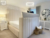 Cream-colored upholstered telly bed with vertical tufted panels and built-in headboard fits tvs small double