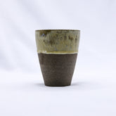 A quadra handmade ceramic tumbler with speckled olive-green glaze and matte dark brown base in ceramic smoked grey stoneware