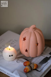 A soft peach-colored terracotta pumpkin tealight holder with star-shaped cutouts perfect for cozy lighting
