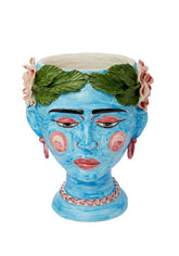 A vibrant blue ceramic testa di moro head planter with green leafy wreath and pink flowers on the headband