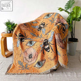 Orange woven bumble bee tapestry throw with black and white bees, blue eyes, pink flowers, and green leaves
