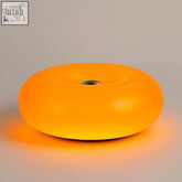 The donut lamp is a glowing orange ambient orange lamp with a smooth translucent plastic body and a metal center hole