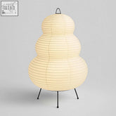 The cream-colored Japanese hikaru lamp features rice paper tiers on an iron tripod stand for soft lighting